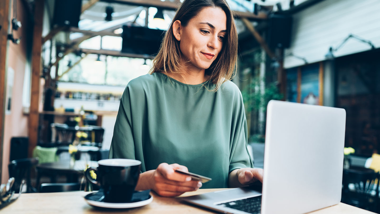 Mujer usando su notebook mientras toma un cafe